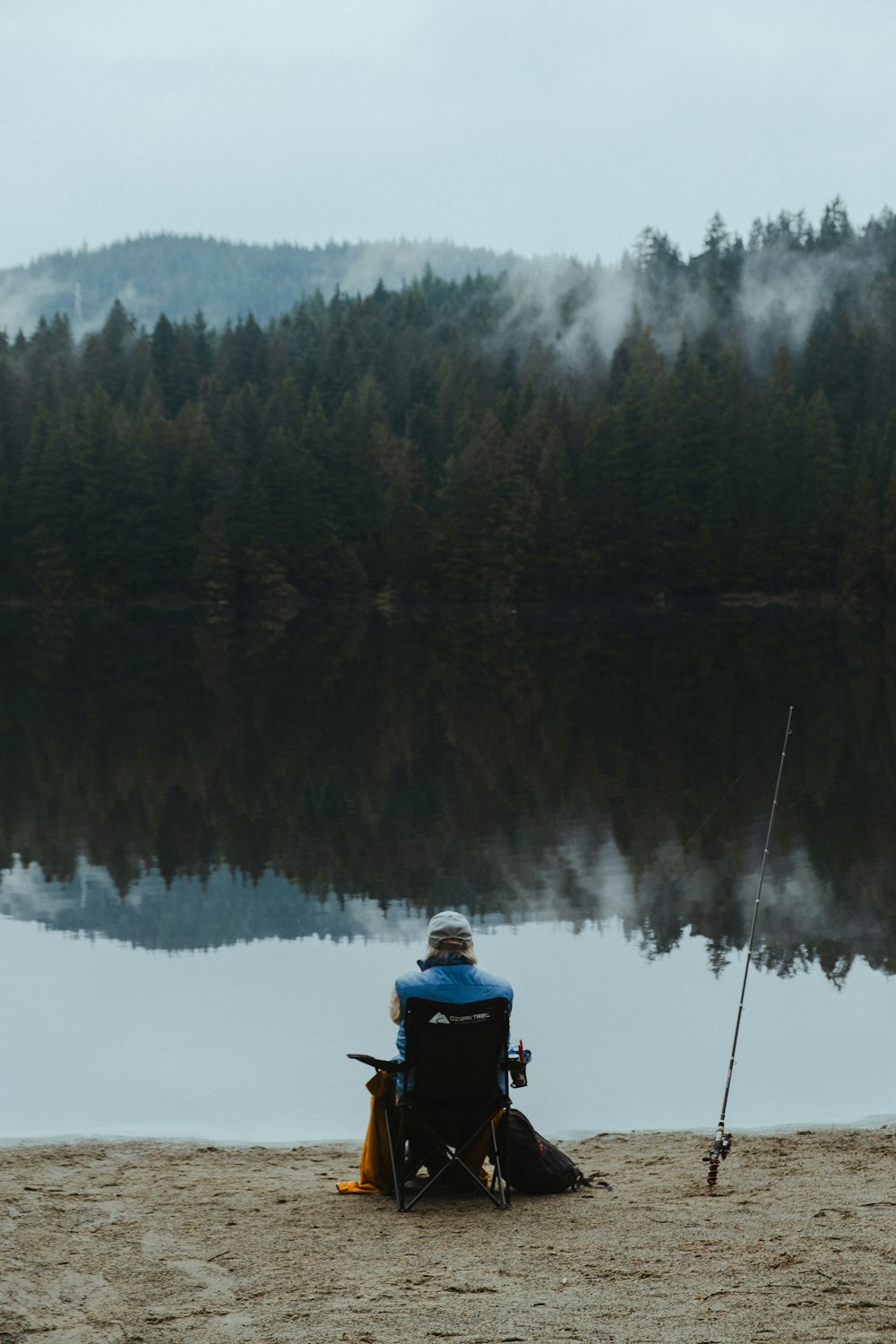 a man sitting on a beach next to a lake