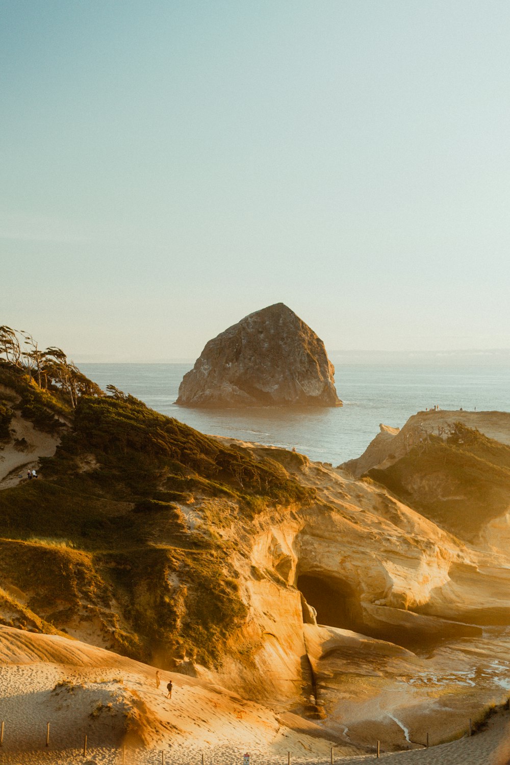 a view of a beach with a large rock in the background