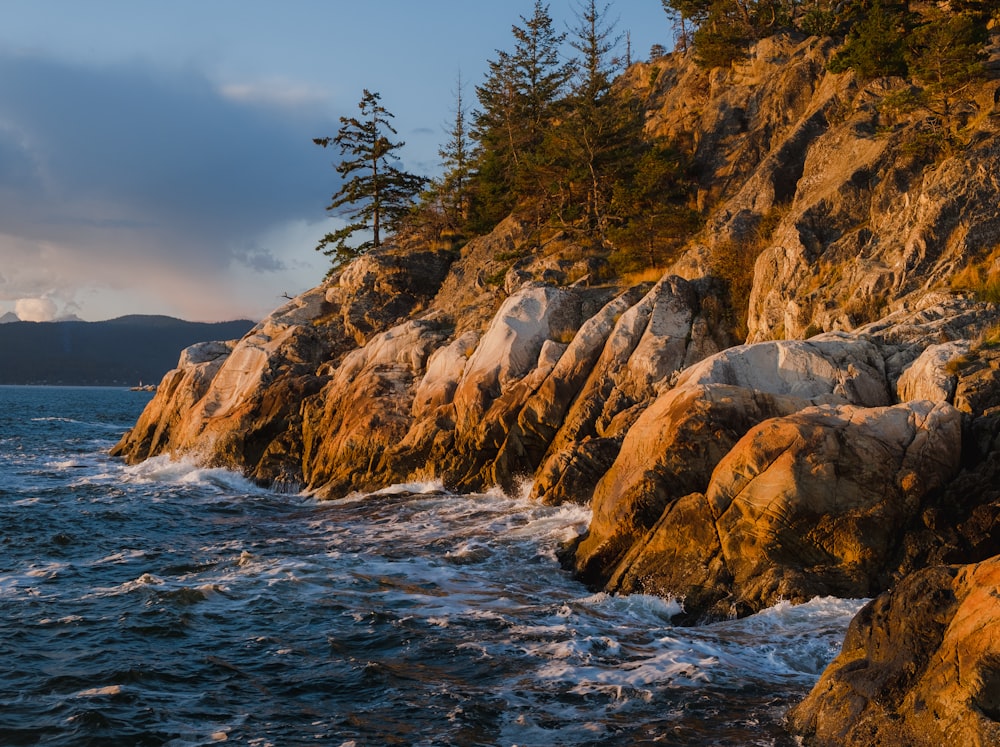 a rocky shore line with waves crashing against the rocks