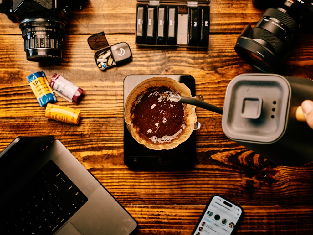 a wooden table topped with a laptop computer and camera