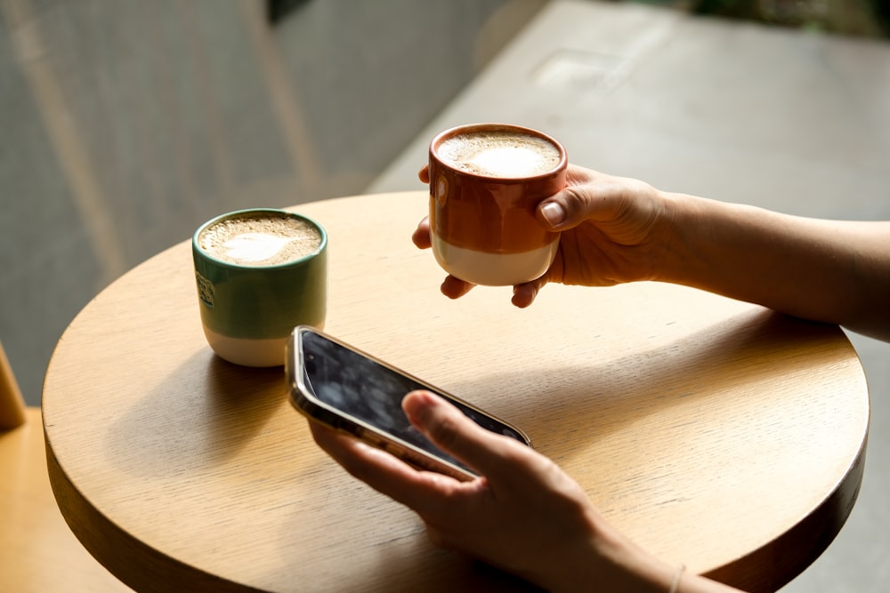 a person holding a cup of coffee and a cell phone