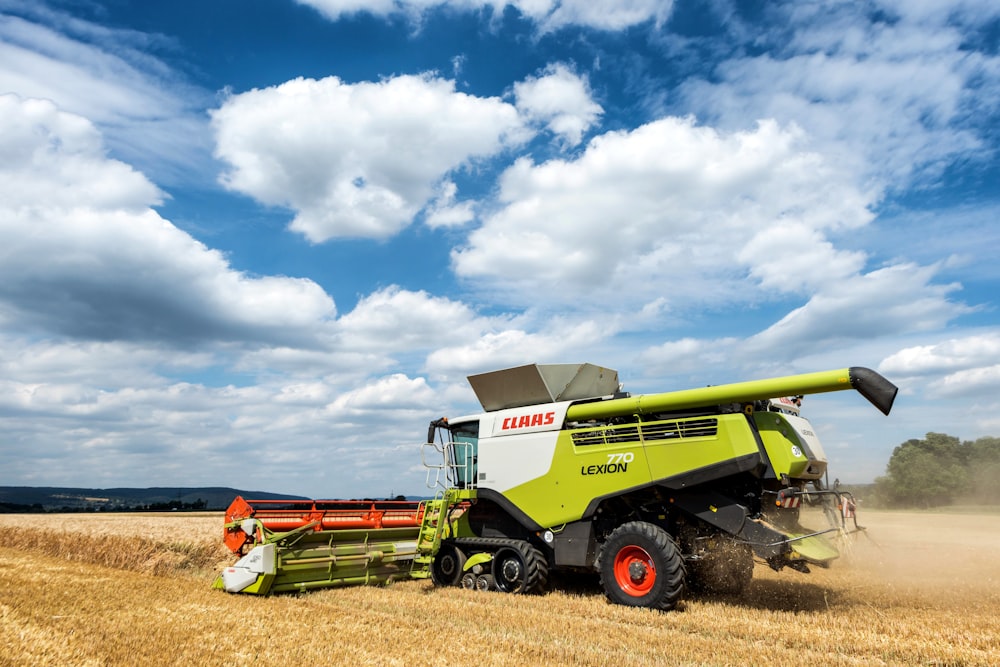 a green and white combine truck driving through a wheat field