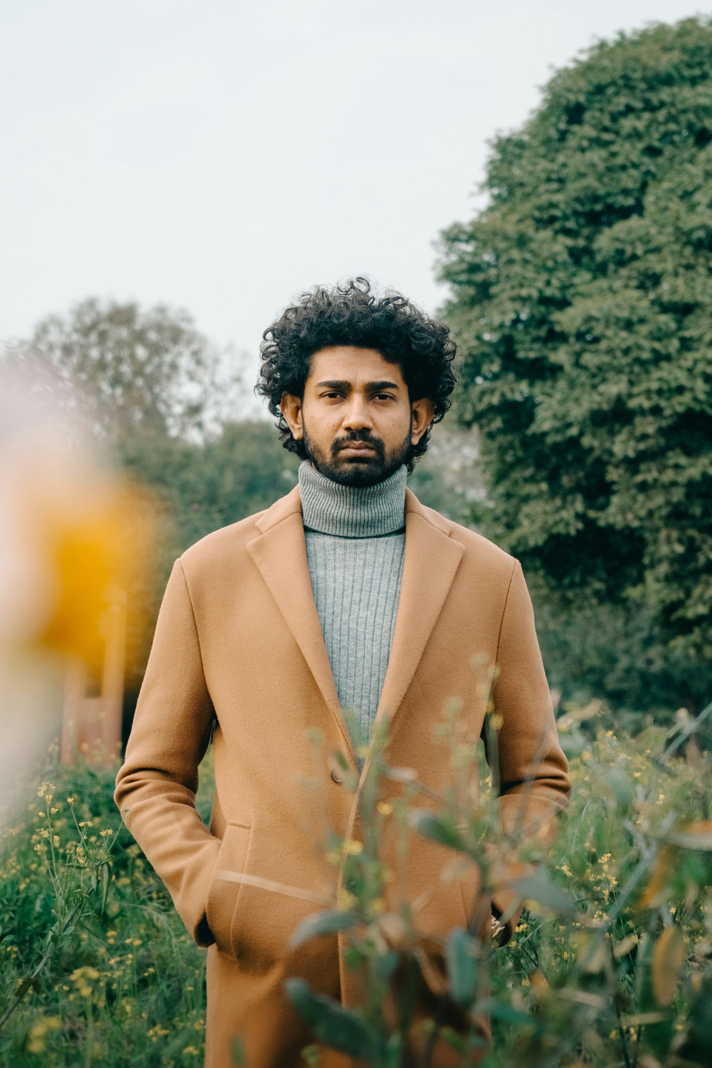 un hombre parado en un campo con las manos en los bolsillos