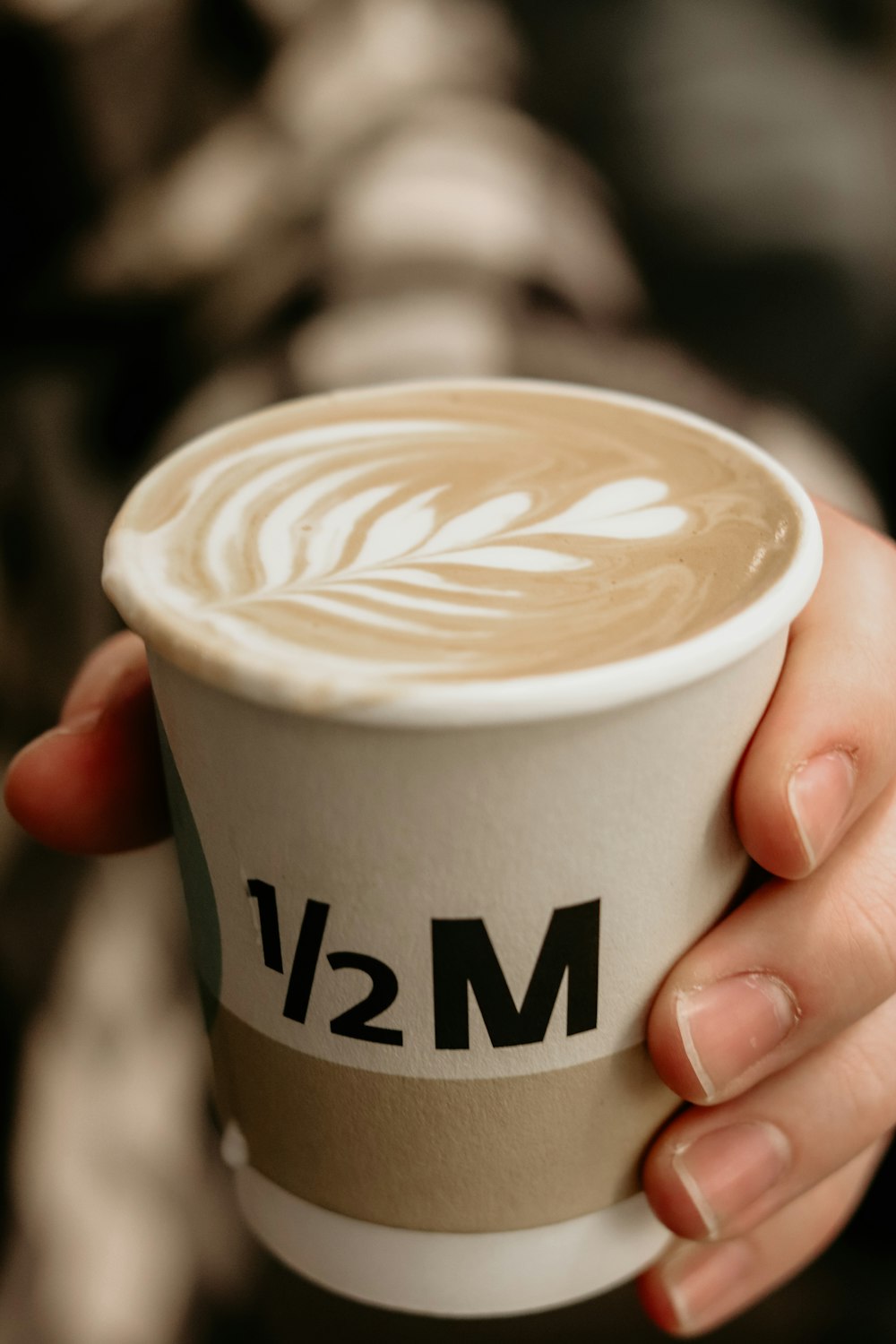a person holding a cup of coffee with the number 12 on it