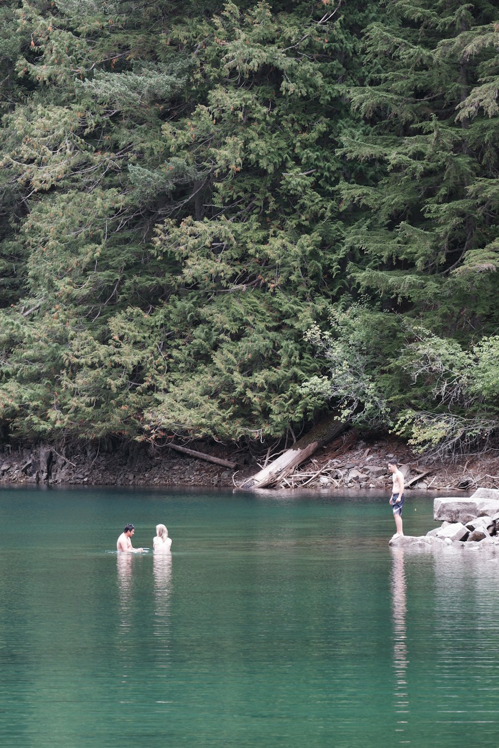 un uomo in piedi su una roccia in mezzo a un lago