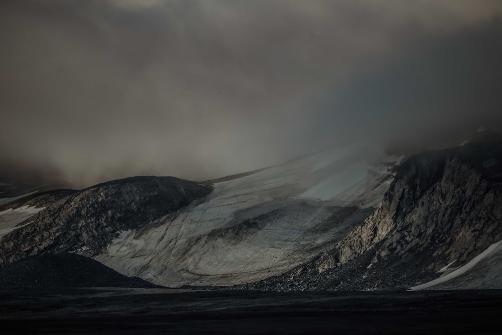 a mountain covered in snow under a cloudy sky