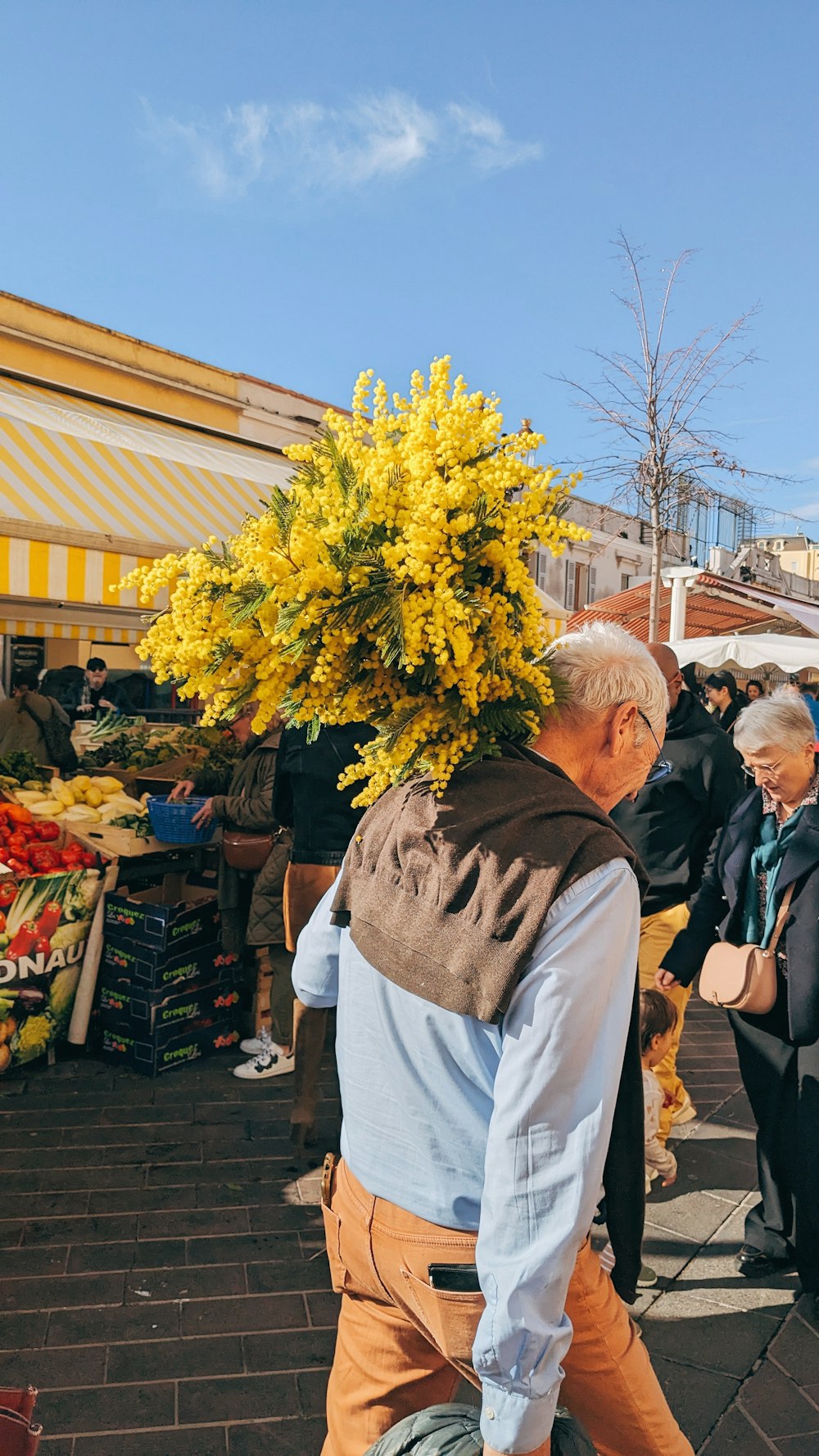 a man walking down a street carrying a bunch of flowers