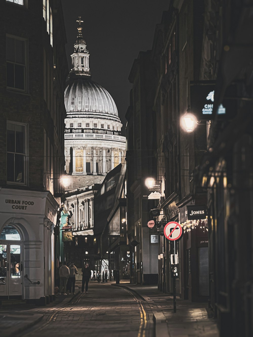 a city street at night with a domed building in the background