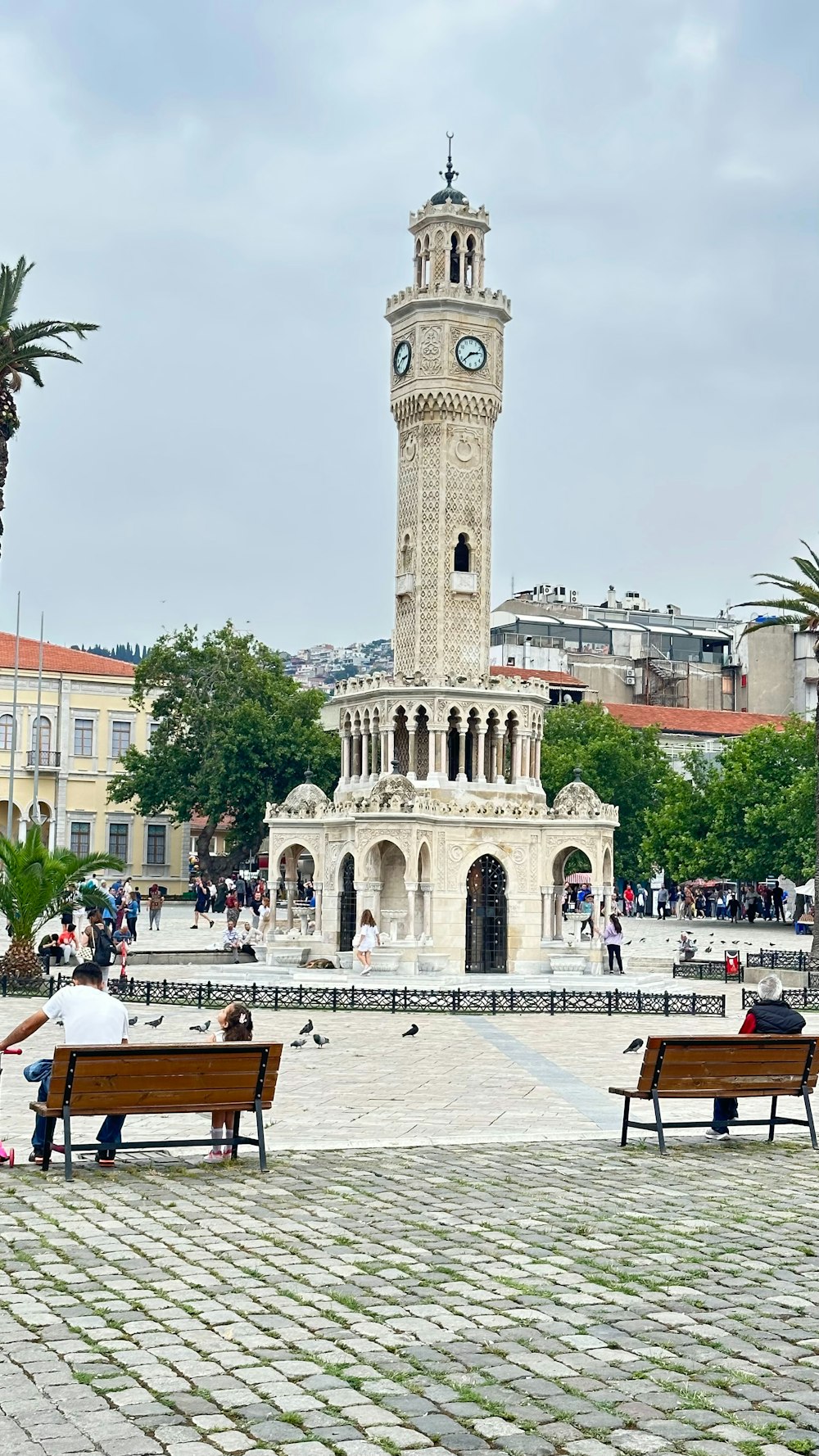 Deux personnes assises sur des bancs devant une tour de l’horloge