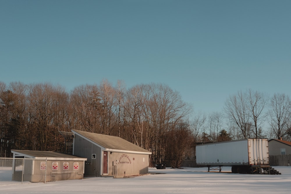 a snow covered field next to a building and trees