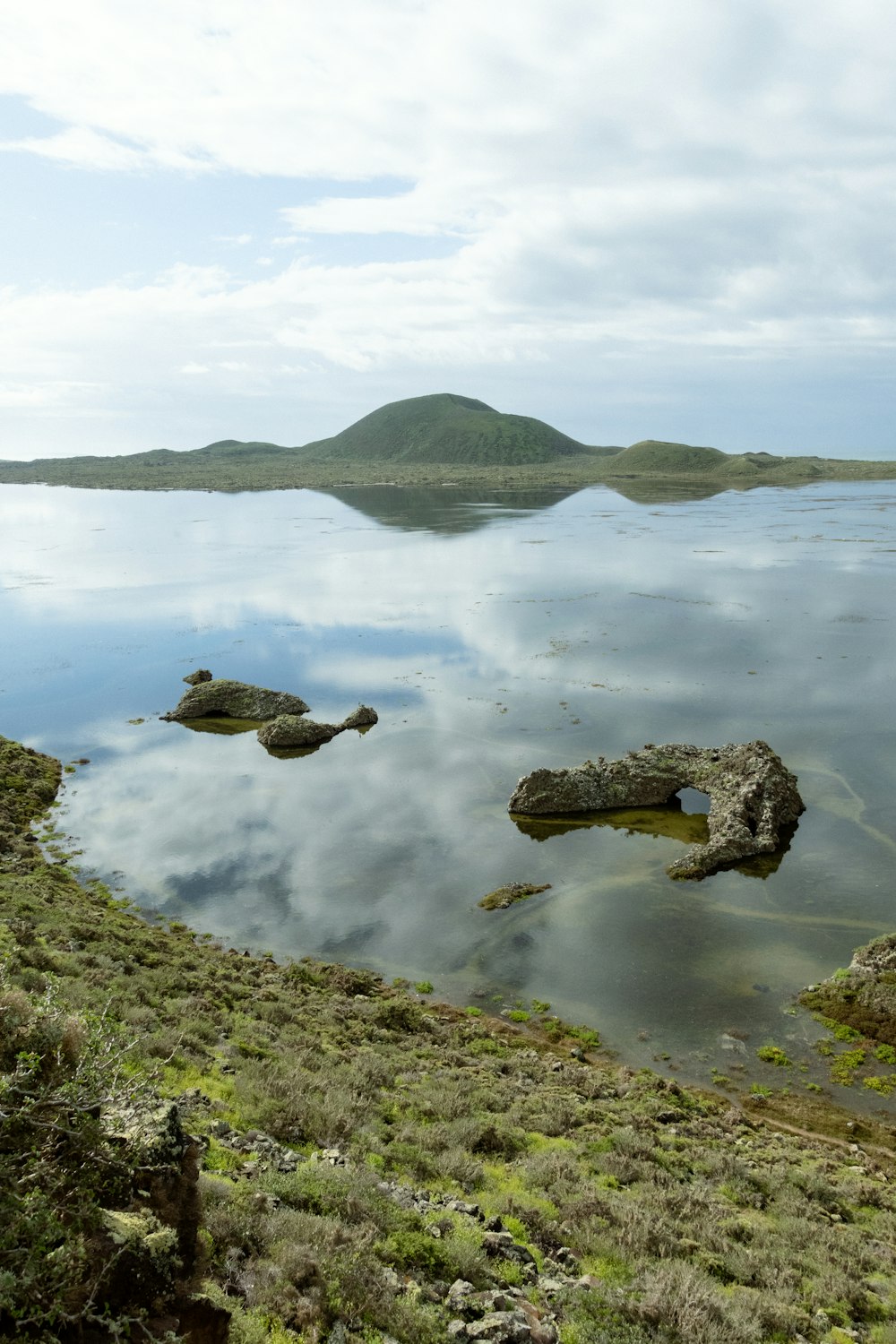 a large body of water surrounded by a lush green hillside