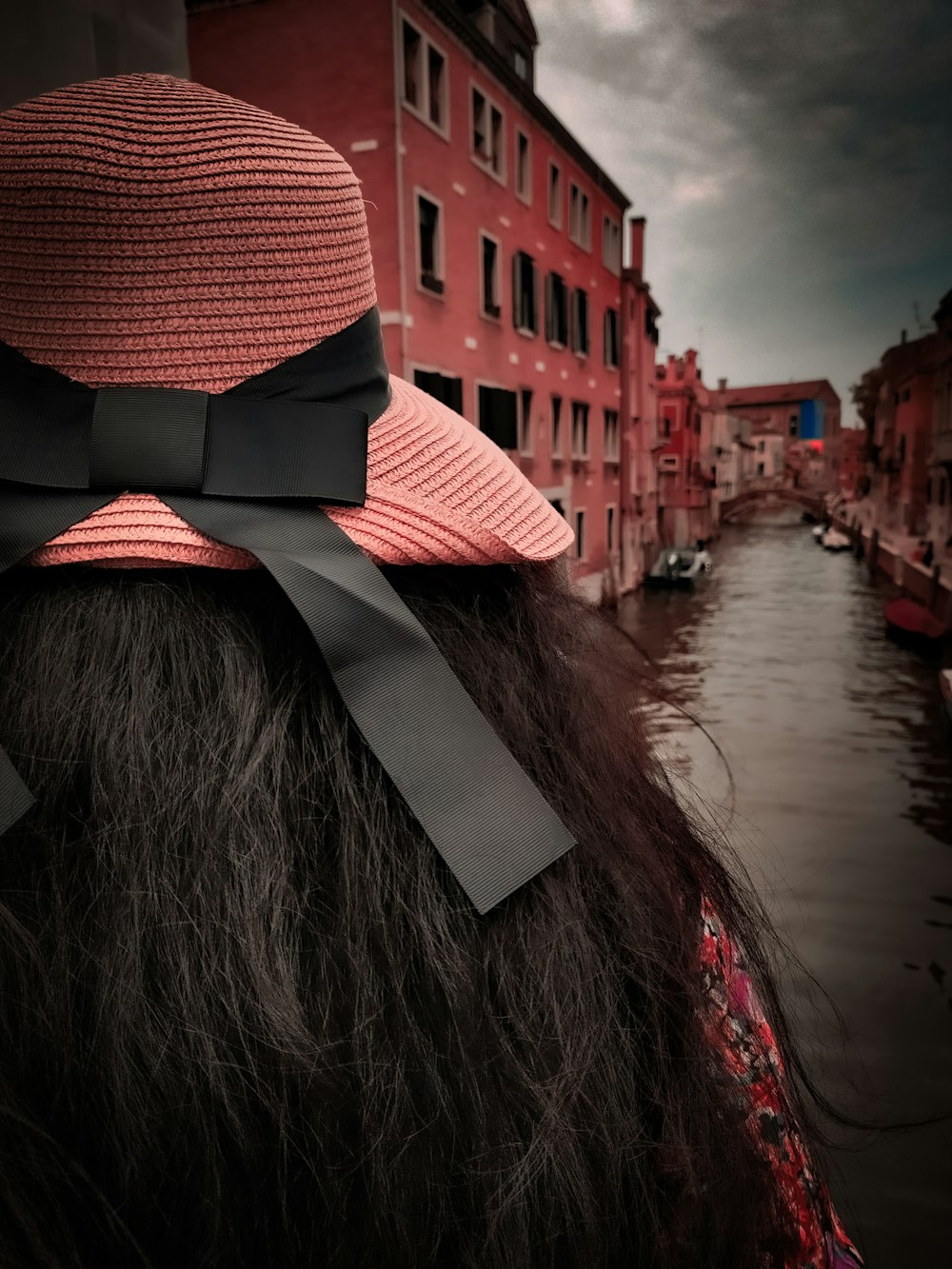 a woman wearing a pink hat with a black bow