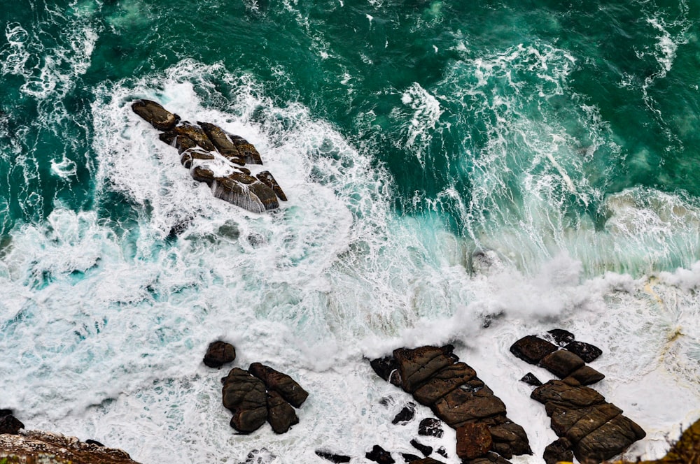 an aerial view of the ocean and rocks