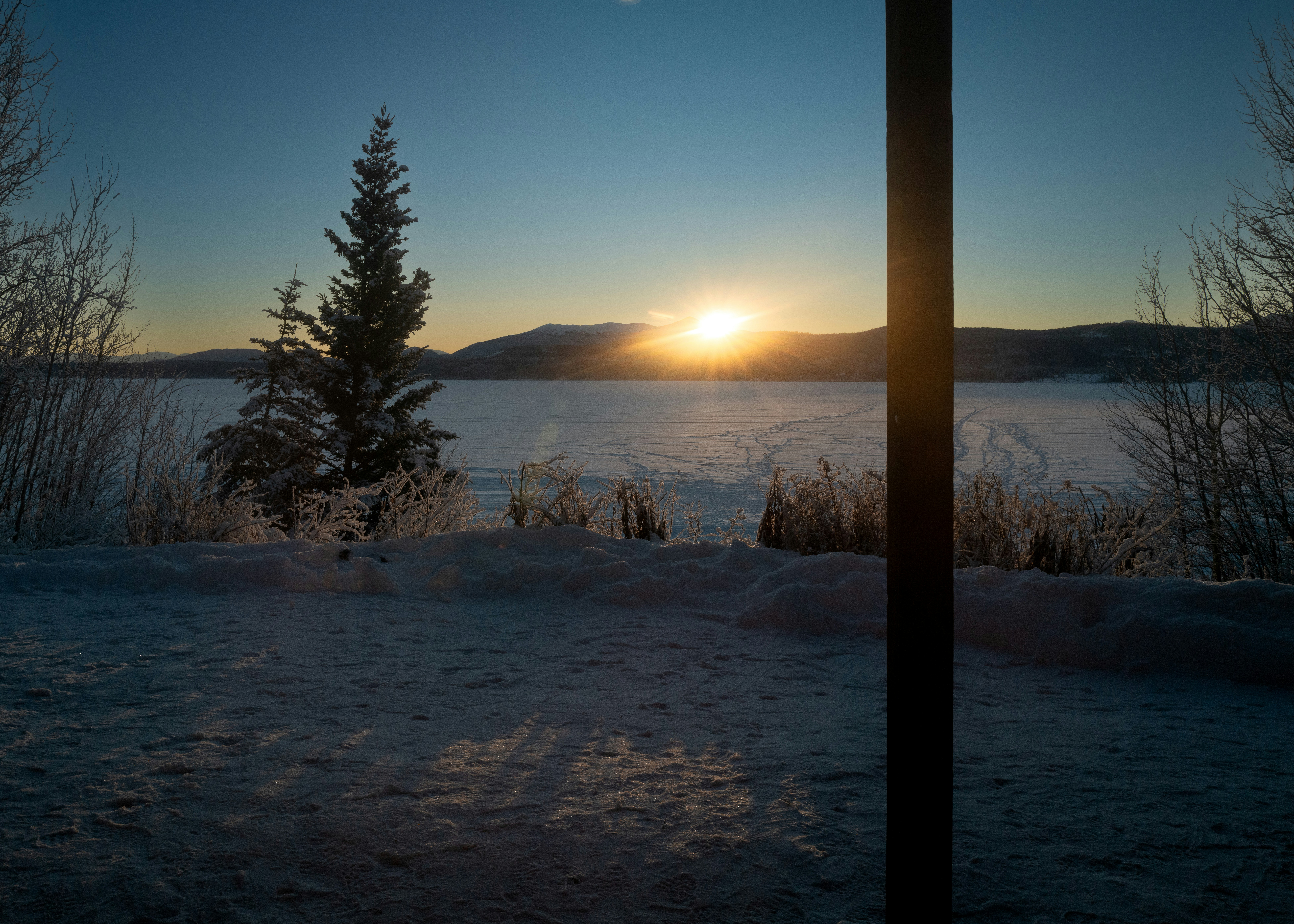 the sun is setting over a frozen lake