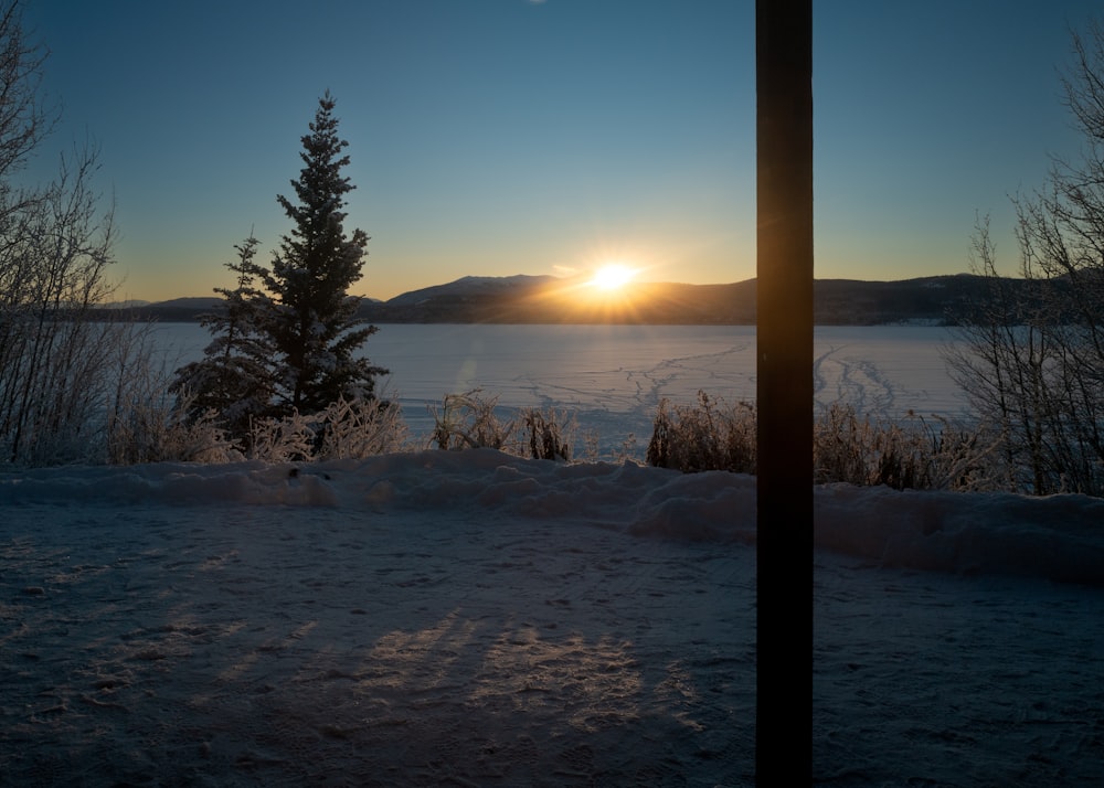 the sun is setting over a frozen lake