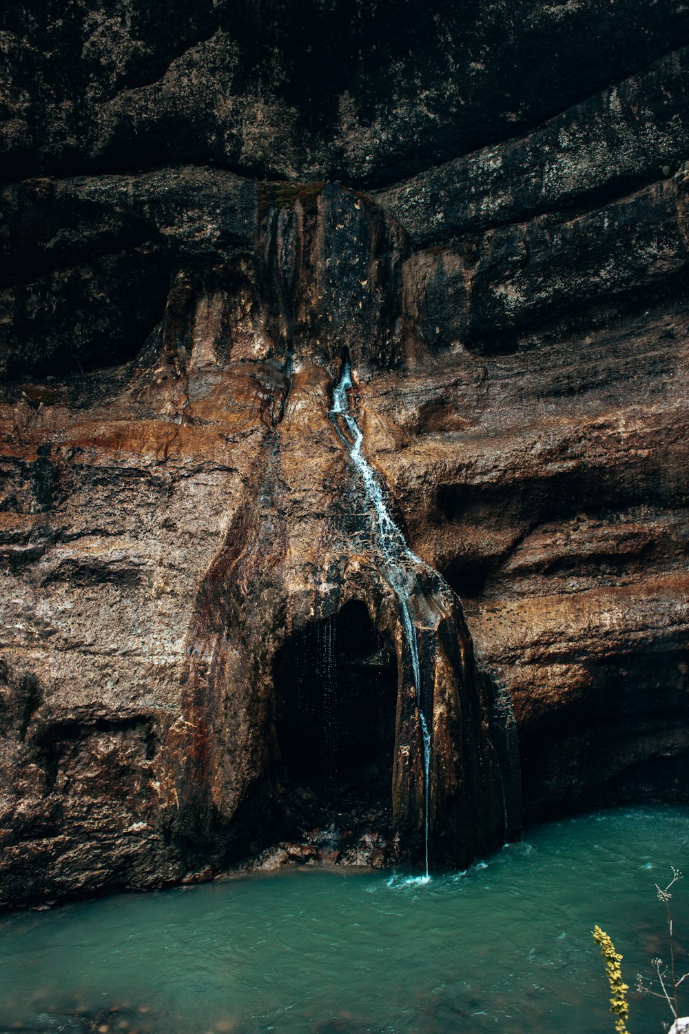 a small waterfall is coming out of a cave