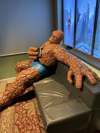 a large statue of a man sitting on a couch in front of a window