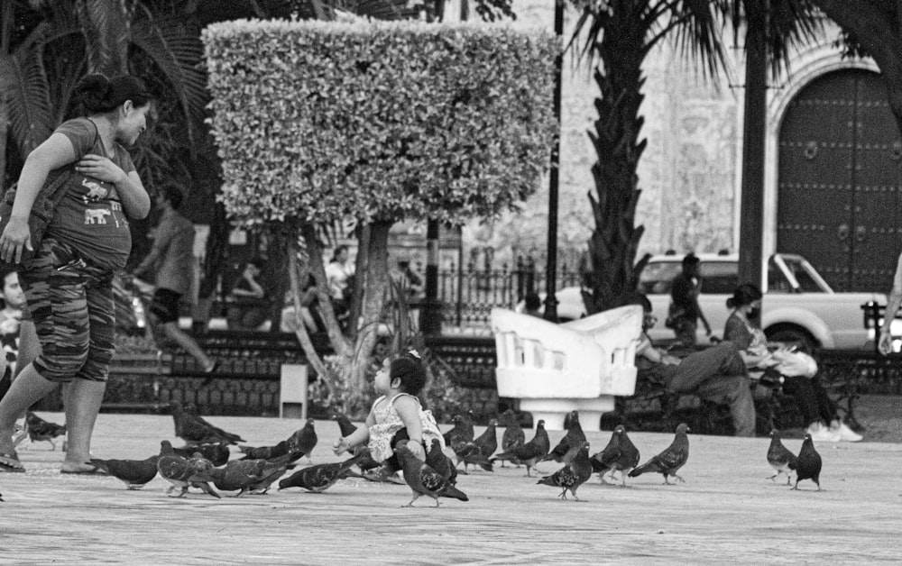 a black and white photo of a man feeding pigeons