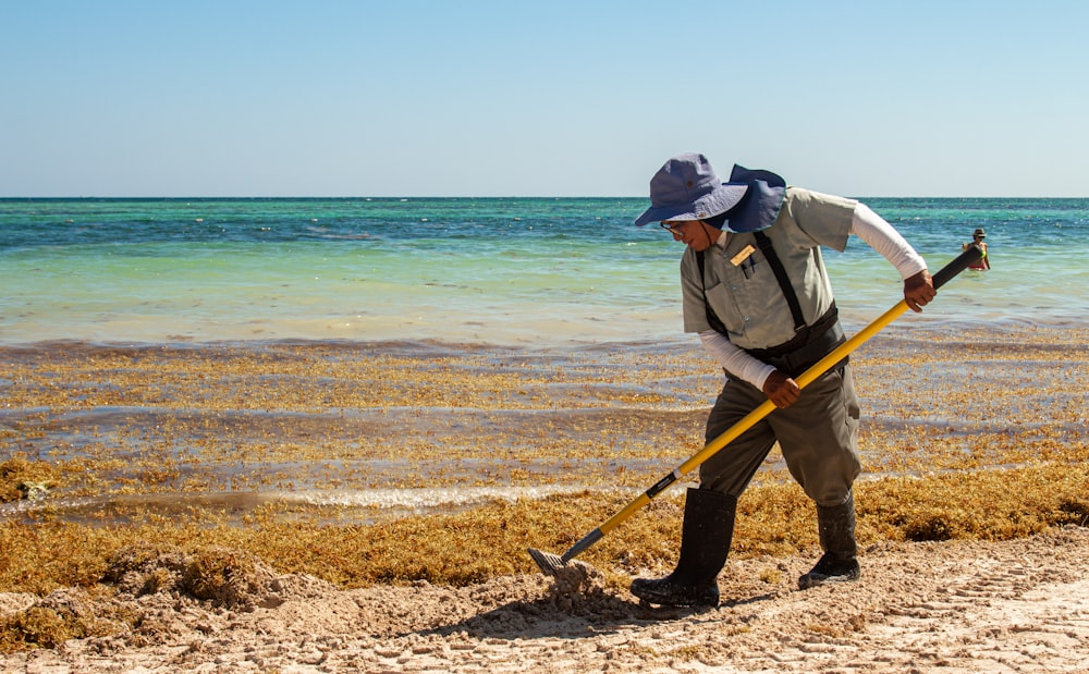 Un homme avec un chapeau et une canne marche le long de la plage