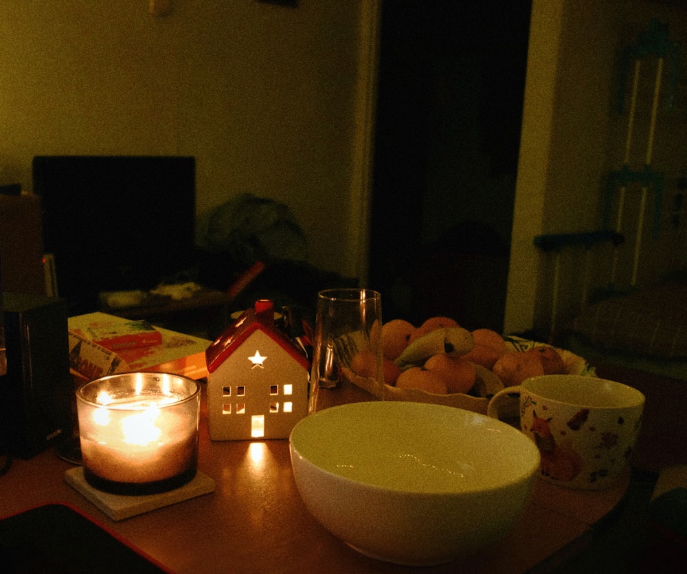 una mesa coronada con un cuenco de fruta y una vela encendida
