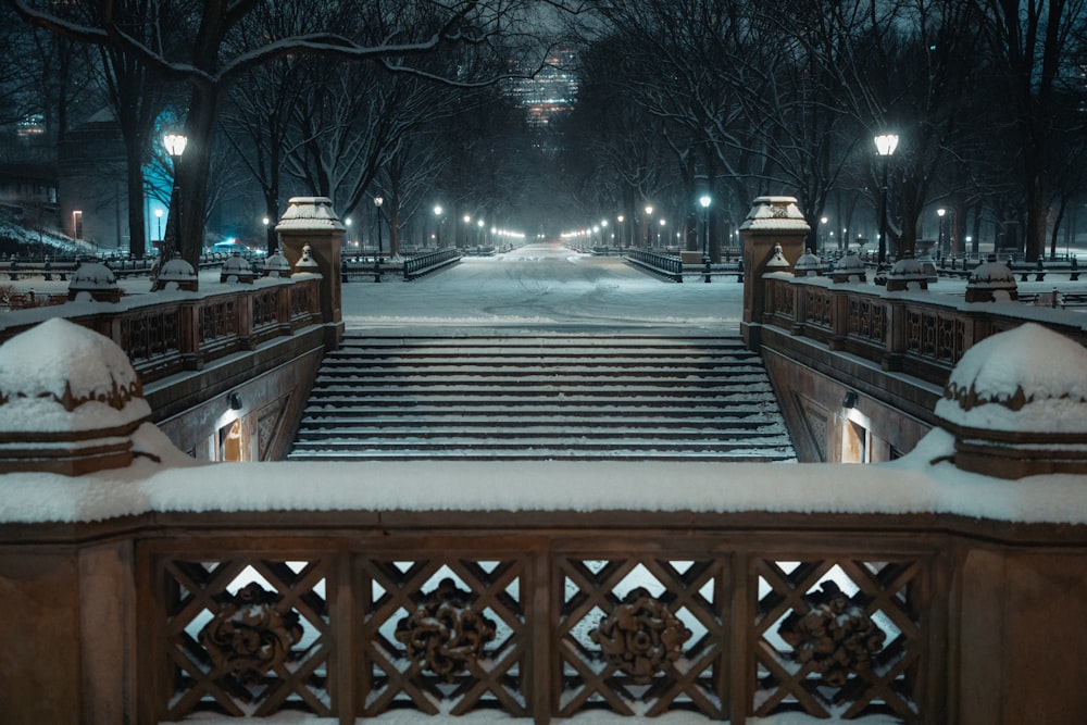 a snowy night in a park with benches and lights