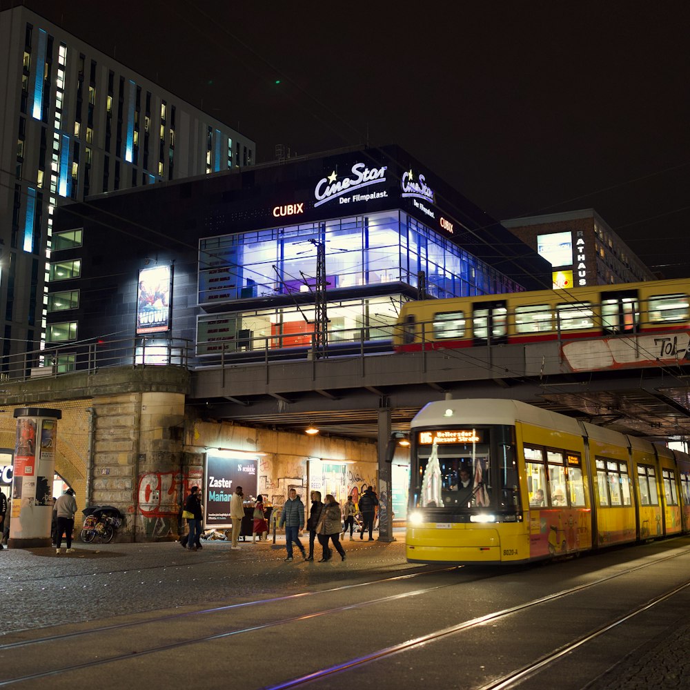 a yellow and white train traveling past a tall building