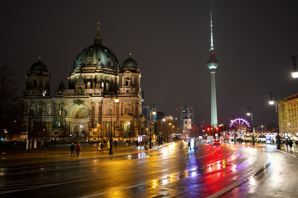 a city street at night with a very tall building in the background