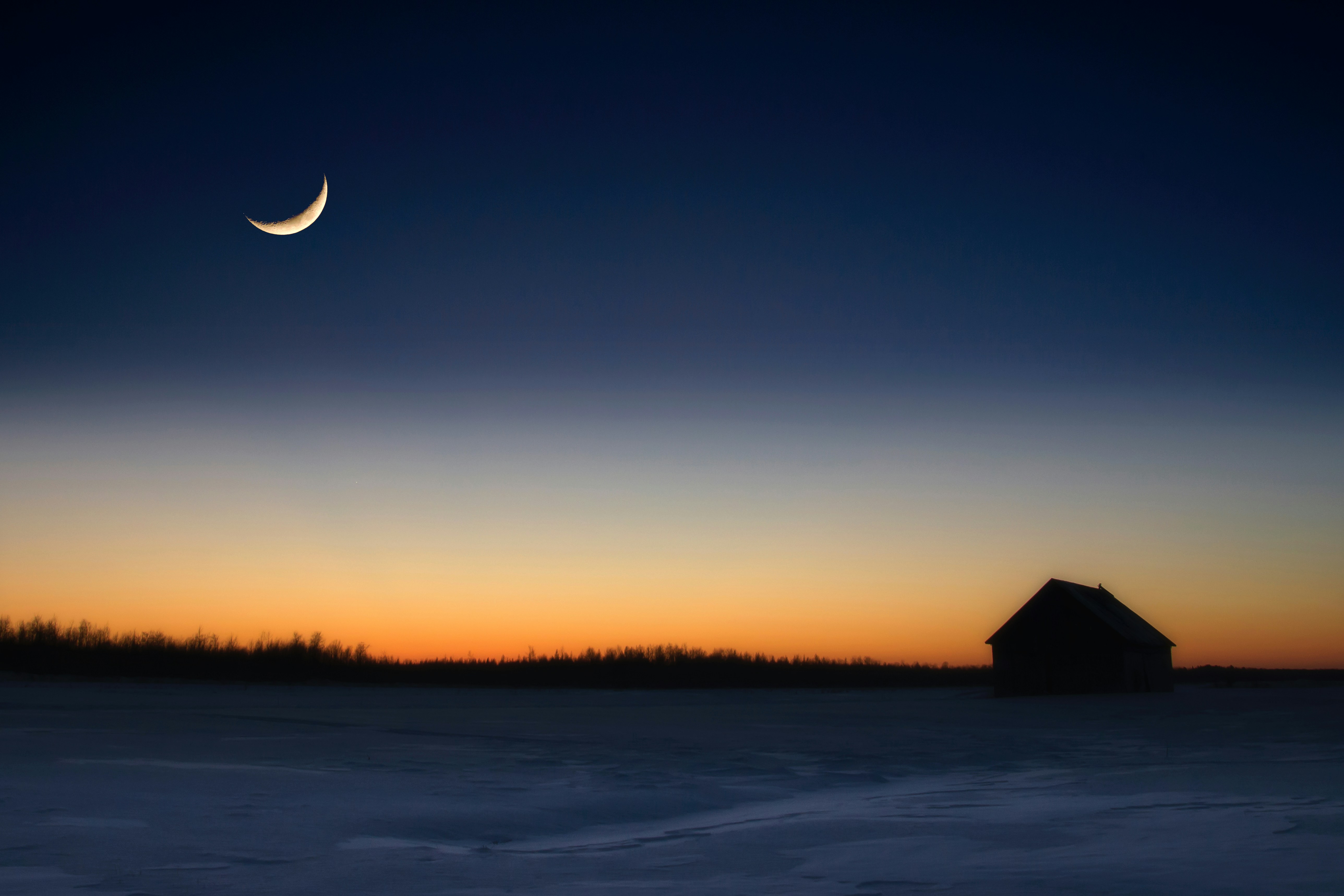 a house in the middle of a field with a half moon in the sky