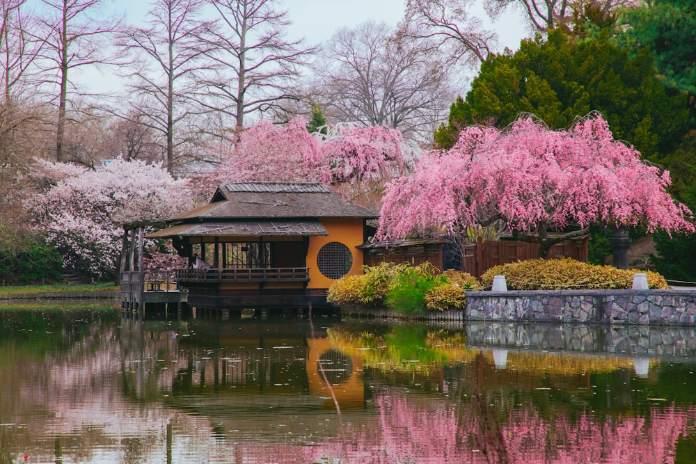 a pond with a gazebo surrounded by blooming trees