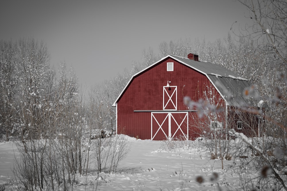 a red barn in the middle of a snowy field