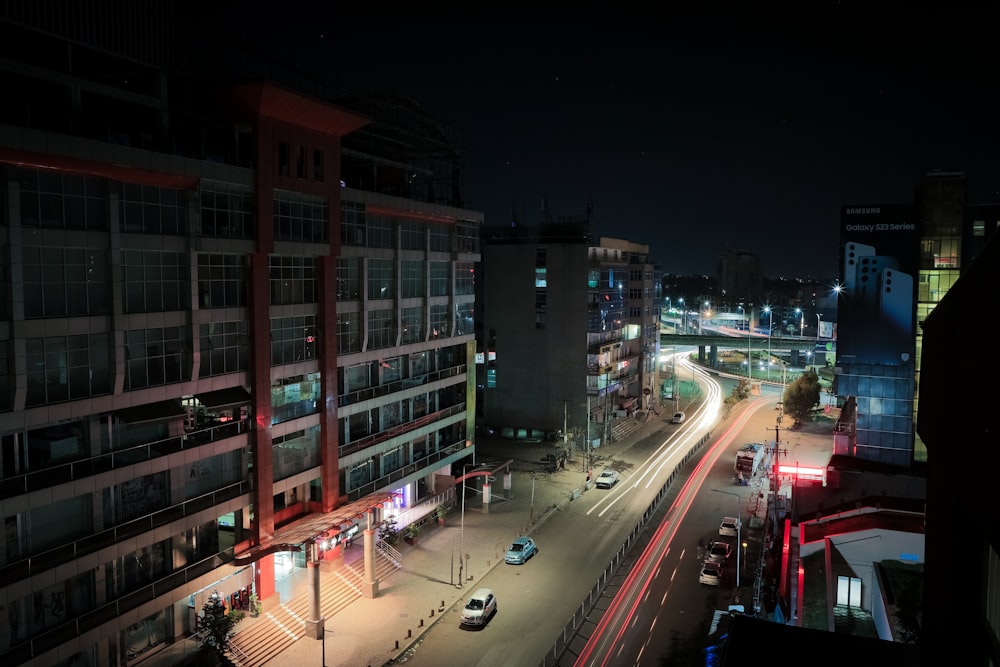 a city street at night with cars driving on it