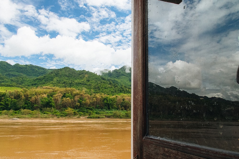 a window with a view of a river and mountains