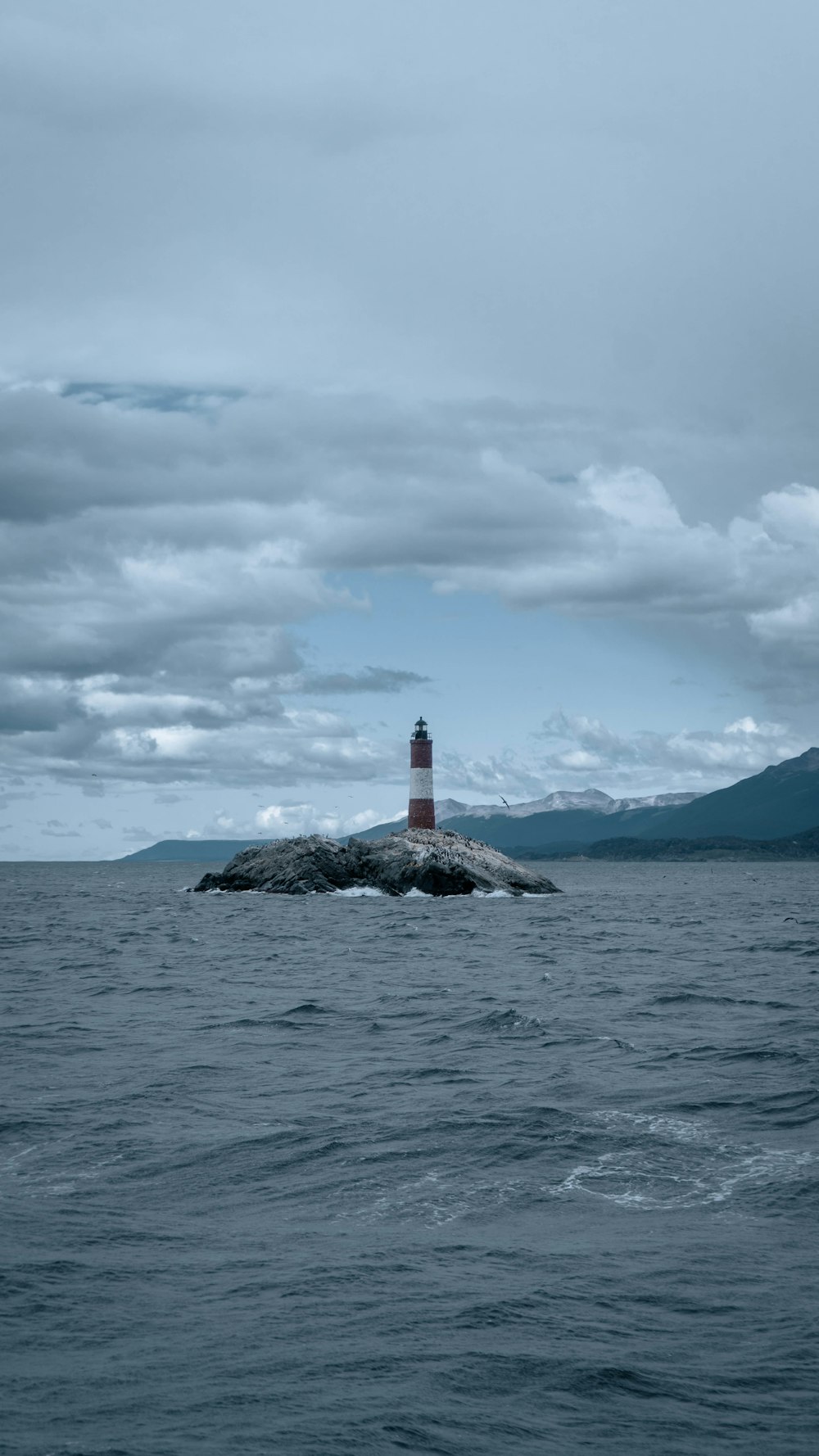 a light house sitting on top of a rock in the middle of the ocean