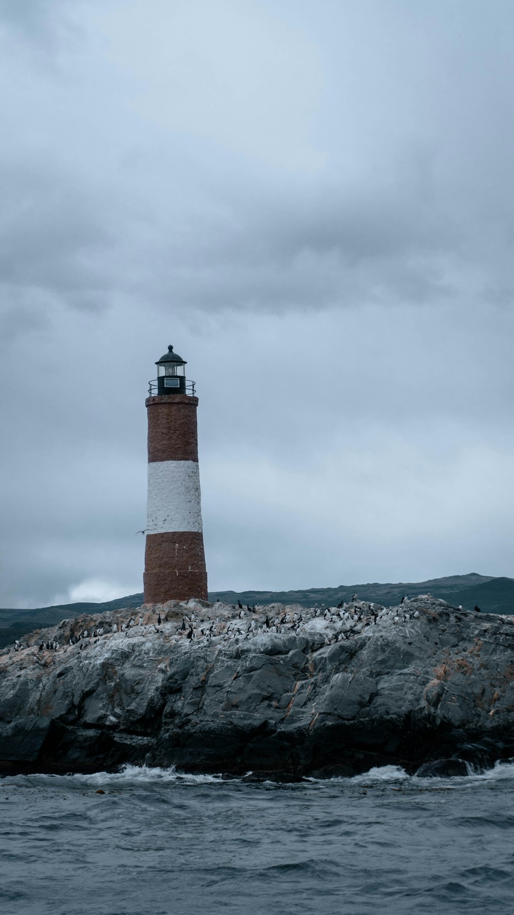 a lighthouse sitting on top of a rock near the ocean