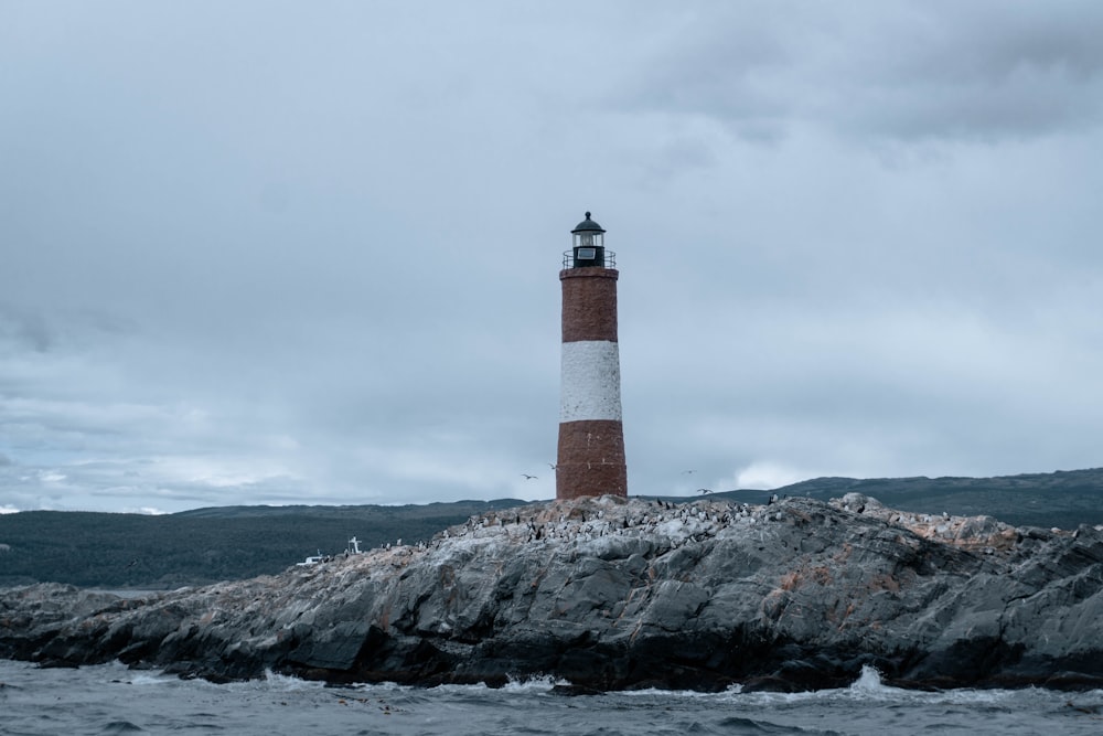 a red and white light house sitting on top of a rock