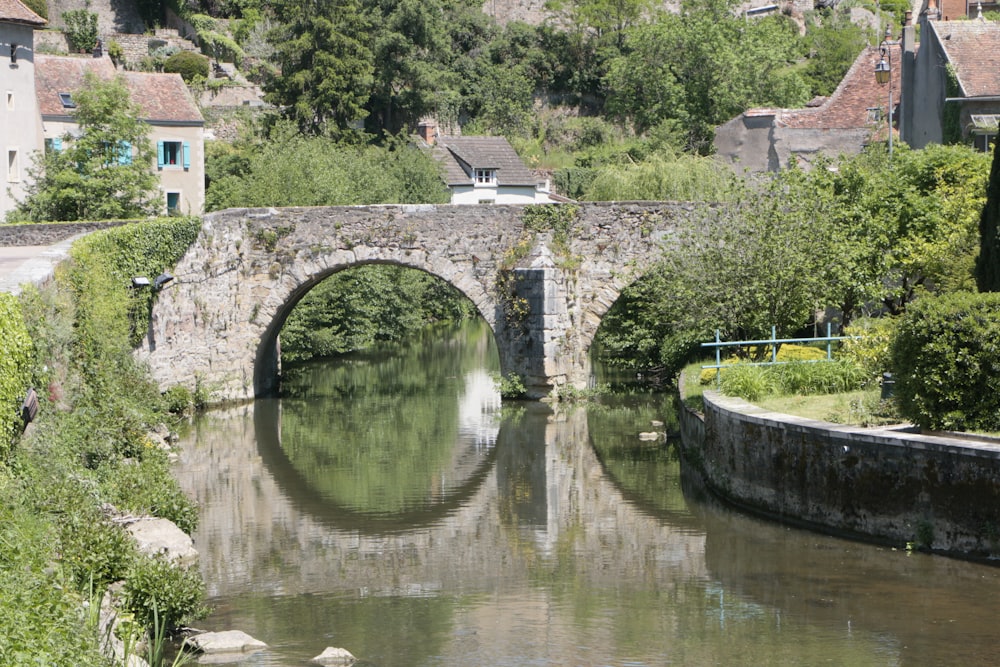 a stone bridge over a river surrounded by trees