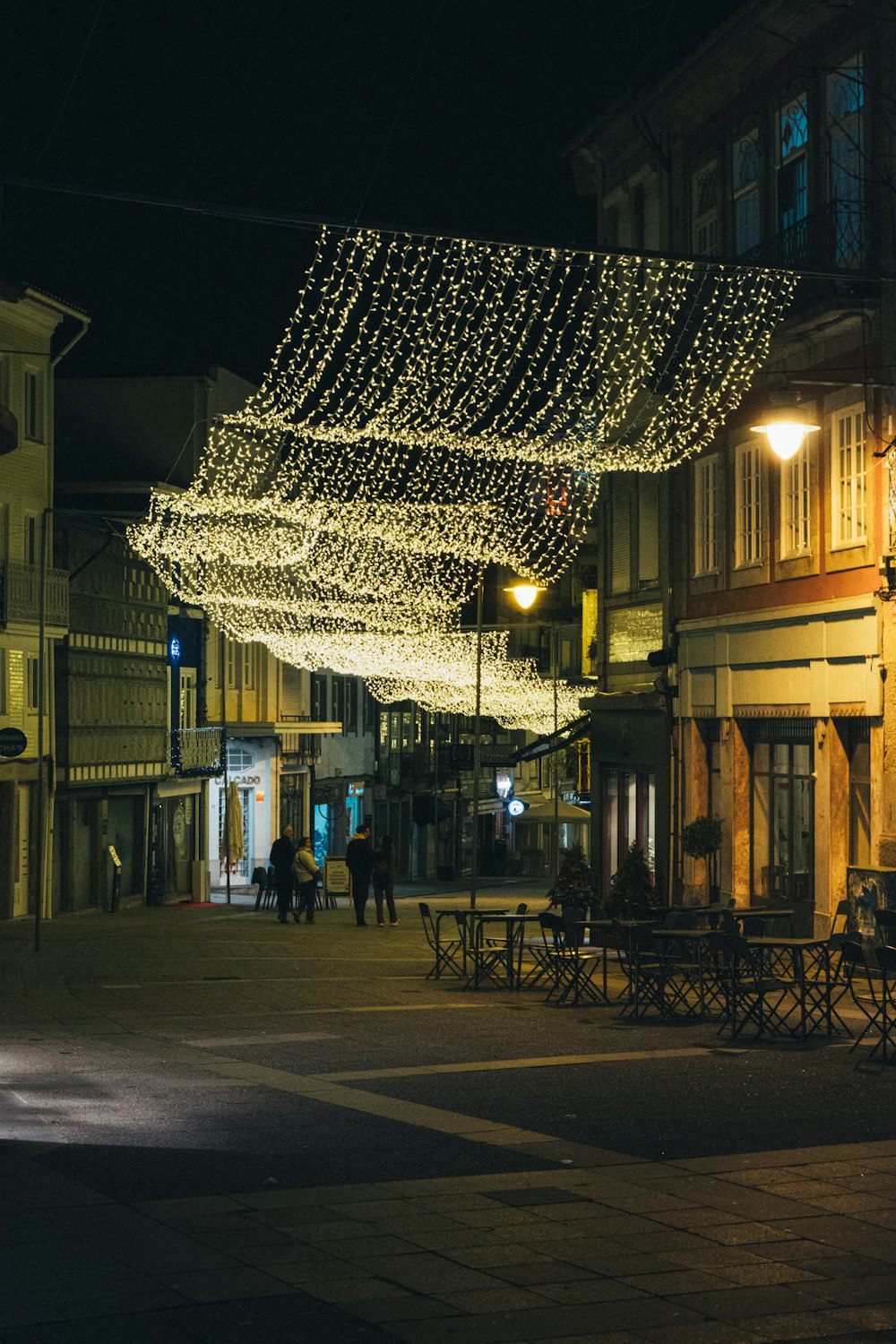 a group of people walking down a street at night