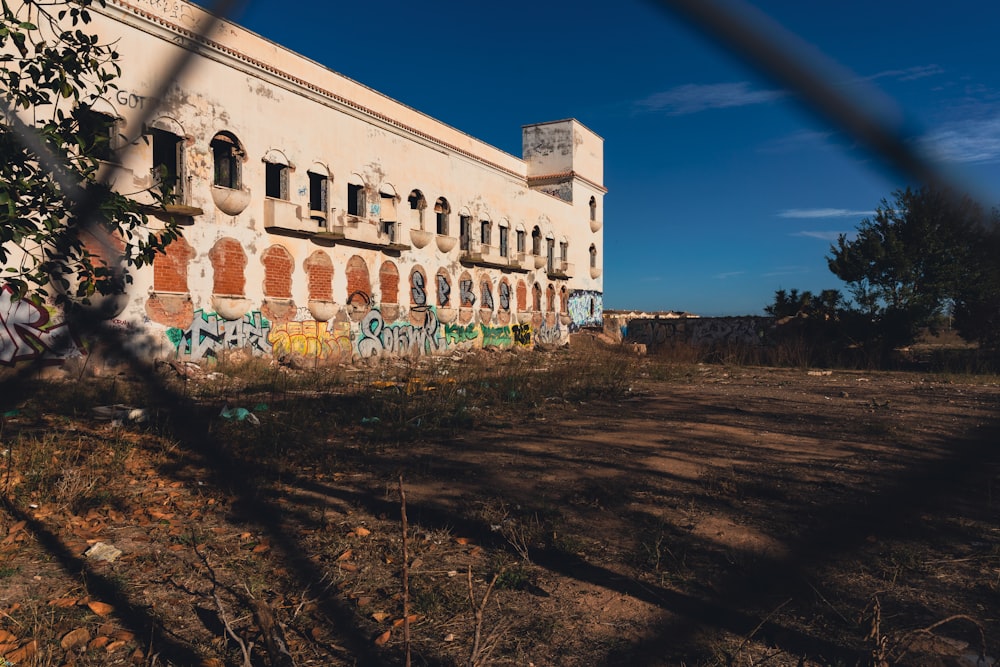 an old building with graffiti on it behind a chain link fence