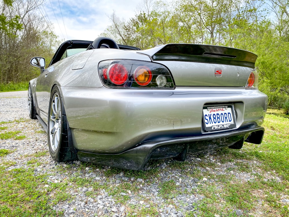 a silver sports car parked on a gravel road