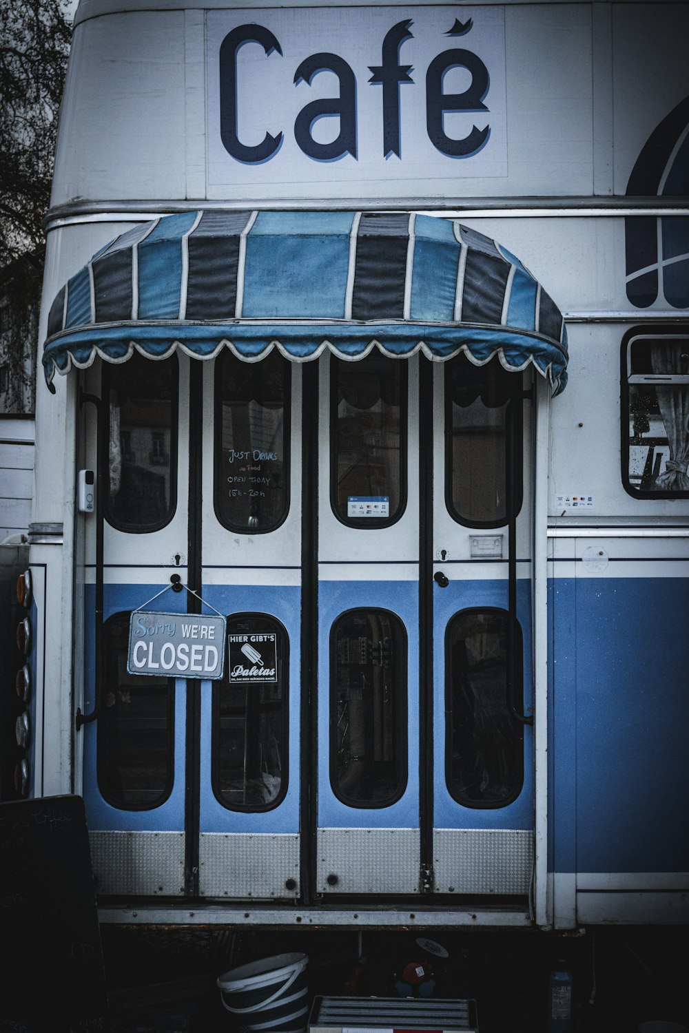 a blue and white bus parked in front of a cafe