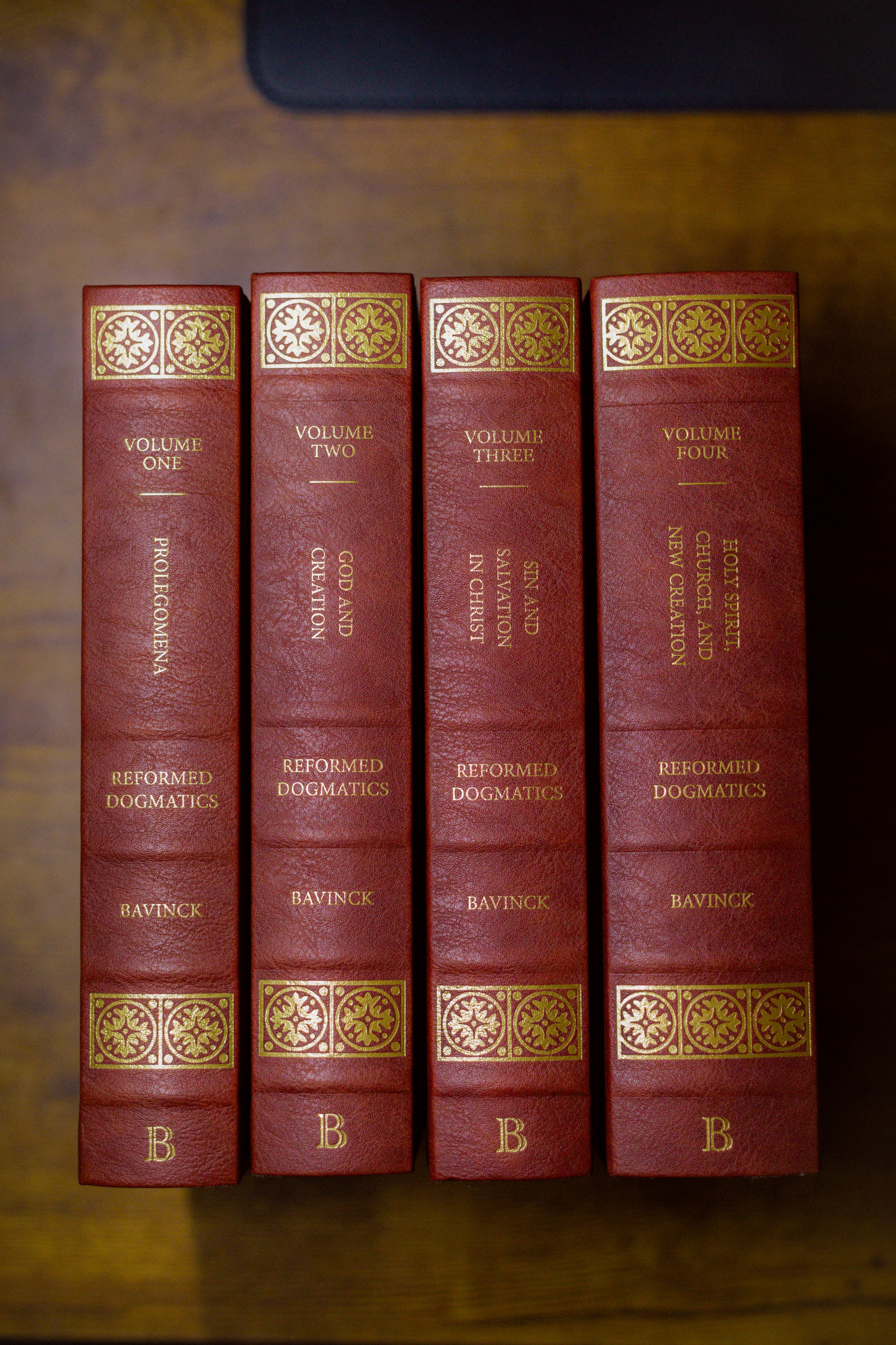 a row of red books sitting on top of a wooden table