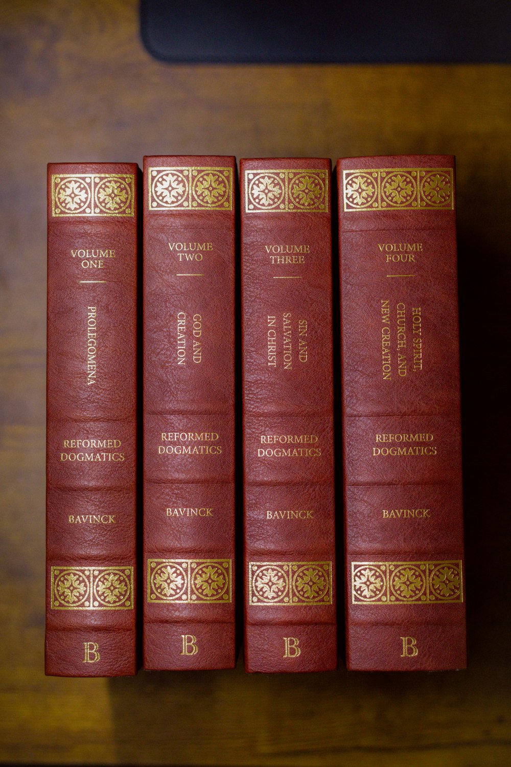 a row of red books sitting on top of a wooden table