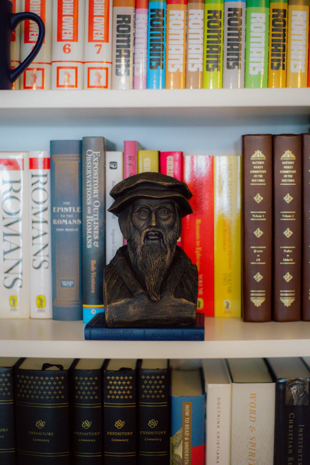 a bookshelf filled with lots of books and a statue of a man