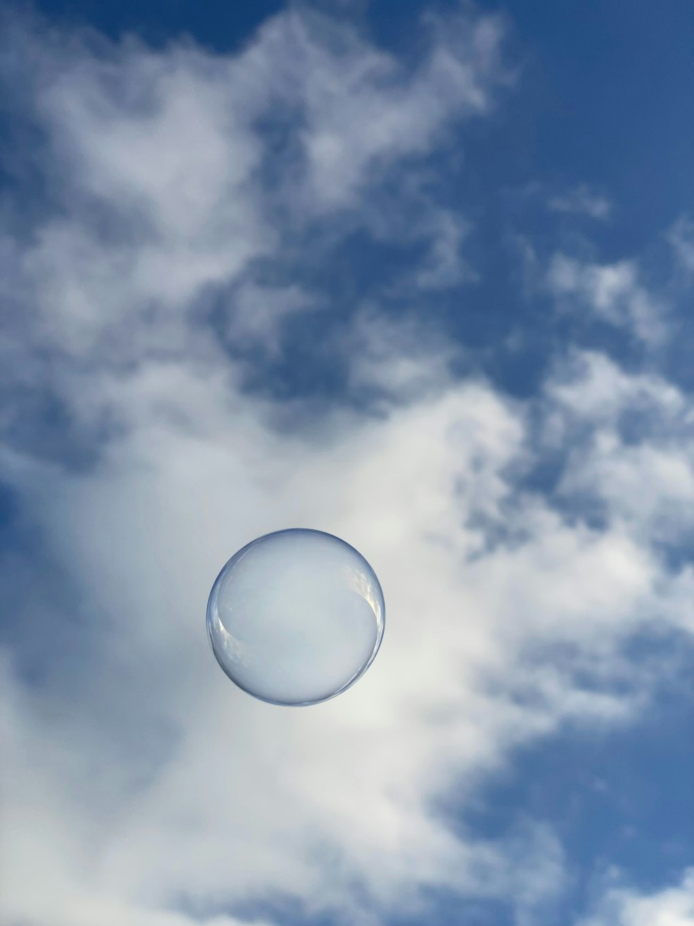 a white frisbee flying through a cloudy blue sky