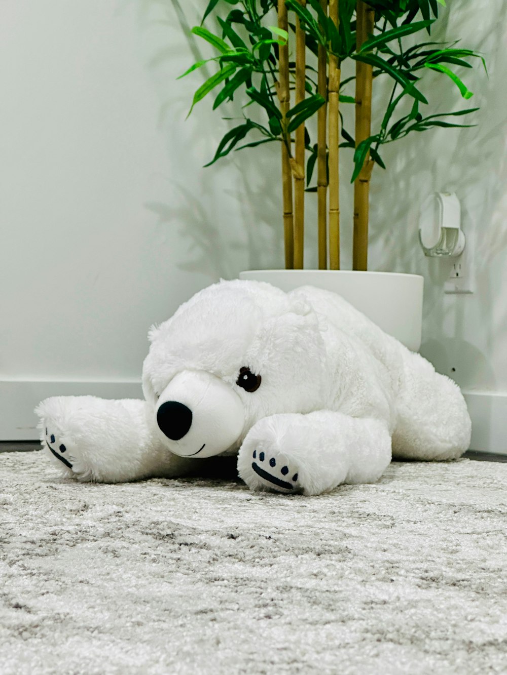 a large white teddy bear laying on the floor