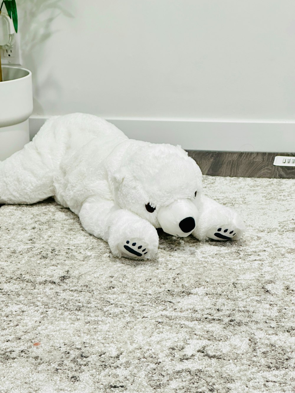 a white teddy bear laying on top of a rug