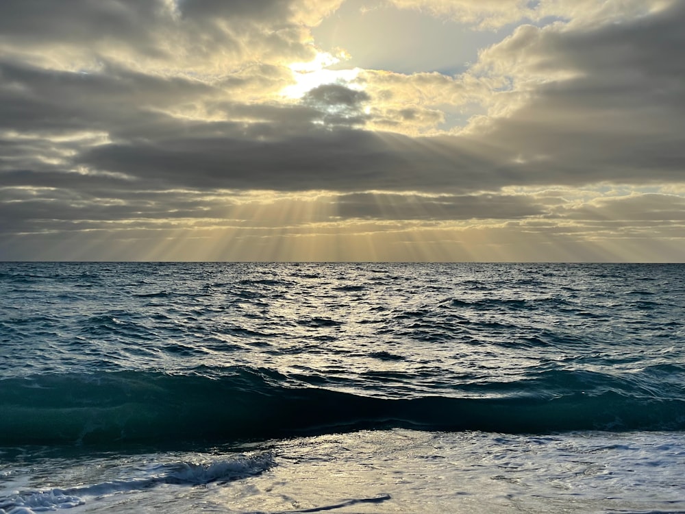 the sun shining through the clouds over the ocean