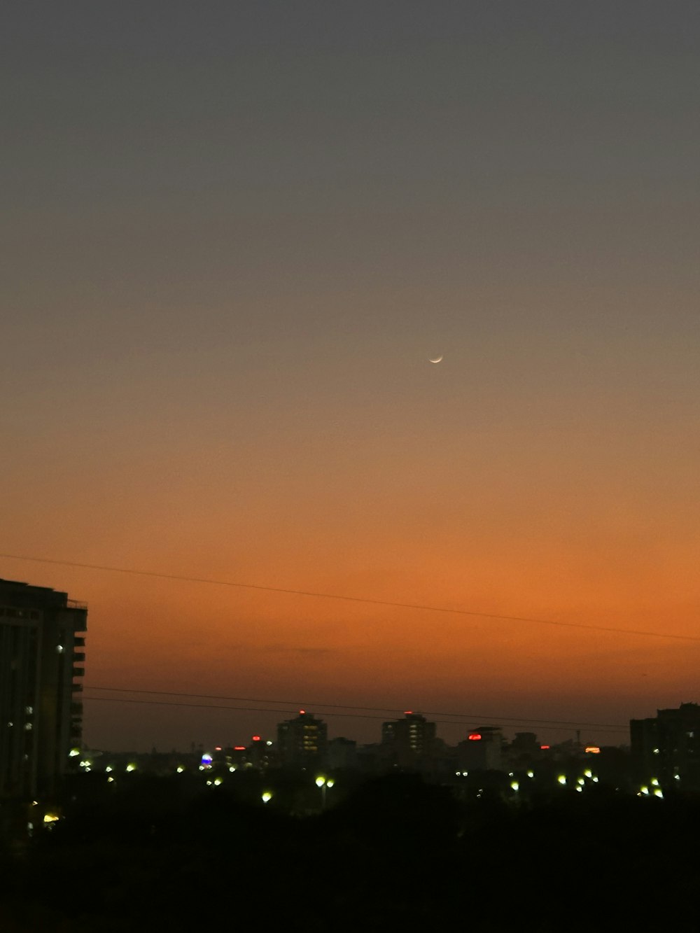 a view of a city at night with a plane flying in the sky