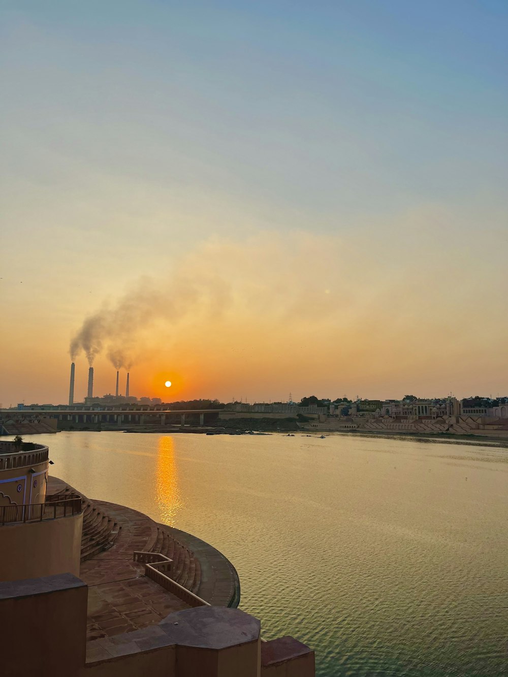 a large body of water with a factory in the background