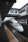 a silver bullet train pulling into a train station